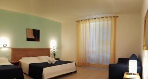una camera d'albergo con due letti e una finestra di Parco Della Rocca a Punta Braccetto