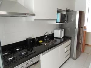 La cuisine est équipée d'une cuisinière, d'un évier et d'un réfrigérateur. dans l'établissement Apartamento 2 quartos Living Park Sul, à Brasilia