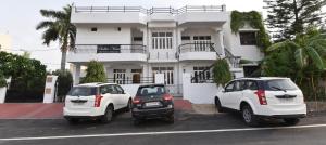 two cars parked in front of a white house at Balbir Niwas Guesthouse Homestay in Udaipur