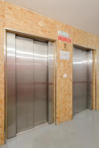 Dos ascensores metálicos en un edificio con una señal en Tomate Rooms en Alicante