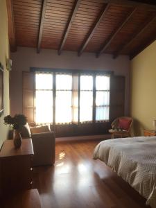 ビリャビシオサにあるAPARTAMENTOS RURALES AZABACHEのベッドルーム1室(窓2つ、ベッド1台、ソファ付)