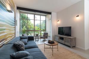 a living room with a blue couch and a television at Yehuda Central Park by TLV2RENT in Tel Aviv