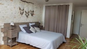 a bedroom with a white bed and a wall at Le pré de la rue in Bouesse