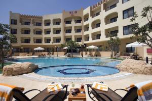 a hotel with a large swimming pool in front of a building at Swiss Inn Plaza Hotel in 6th Of October