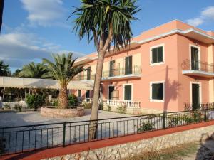 a pink building with palm trees in front of it at Argo Hotel in Perama