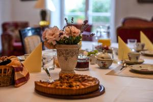 a table with a vase of flowers and a pie at Maras Manor in Turlava