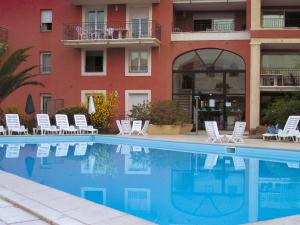 einem Pool vor einem Hotel mit Stühlen und einem Gebäude in der Unterkunft Lagrange Vacances Port-Marine in Sainte-Maxime