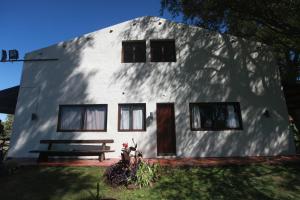 a white building with a bench in front of it at Estancia Termal San Nicanor in Termas de San Nicanor