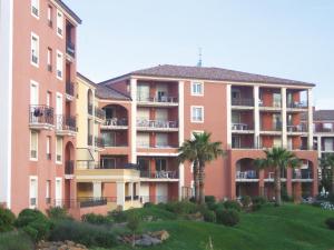 an apartment building with palm trees in front of it at Lagrange Vacances Port-Marine in Sainte-Maxime
