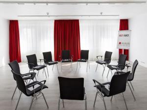 a room with chairs, tables, and a projector screen at DORMERO Hotel Dessau-Roßlau in Dessau