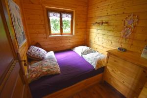 um pequeno quarto com uma cama num chalé de madeira em Chalet à fleur de rêve em Maroilles