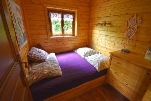 a small room with a bed in a log cabin at Chalet à fleur de rêve in Maroilles