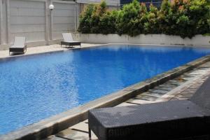 a large swimming pool with two chairs at Tifolia Apartment Pulomas - Kelapa Gading in Jakarta