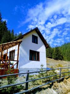 uma pequena casa branca numa colina com uma cerca em Csillag kulcsoshaz em Gheorgheni