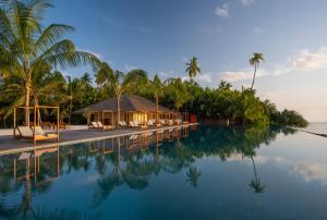 un complexe avec des palmiers et une piscine dans l'établissement The Residence Maldives at Dhigurah, à Gaafu Alifu Atoll