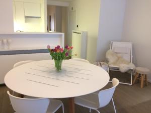 a white table and chairs with a vase of flowers on it at Residentie TYL - Leopoldlaan 122 in Knokke-Heist