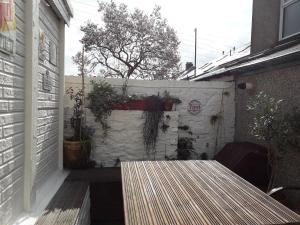 a patio with a wooden table and a wall at Tŷ Selah, Rugby Ave, Neath in Neath