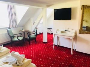 ein Hotelzimmer mit einem roten Teppich, einem Tisch und Stühlen in der Unterkunft Hotel Alt Görlitz in Görlitz
