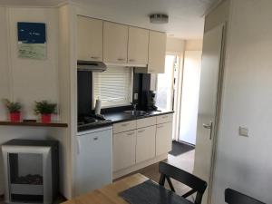 a kitchen with white cabinets and a table and a stove at Blauwe Zeedistel in IJmuiden