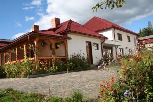 a white house with a red roof and some flowers at Cabana Iza in Bîrsana