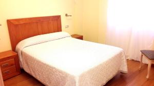 ビラノーバ・デ・アロウサにあるVistas de Arosaの白いベッド1台(木製ヘッドボード付)が備わるベッドルーム1室が備わります。