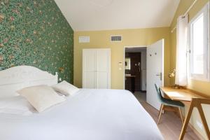 una camera con letto bianco e scrivania di Hôtel Central ad Avignone