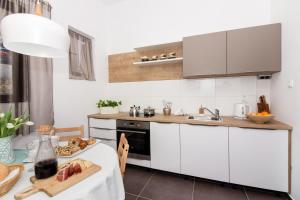 una cocina con armarios blancos y una mesa con un plato de comida en Apartment One, en Okrug Donji