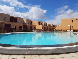 a large swimming pool in front of some apartments at La Perla de Bahia Sol in Caleta De Fuste