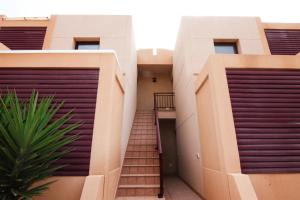 a stairway between two buildings with purple garage doors at La Perla de Bahia Sol in Caleta De Fuste