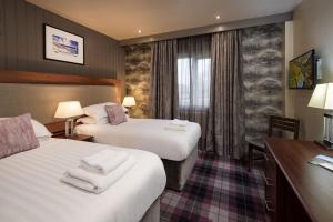 a hotel room with two beds and a desk at The Seaton Lane Inn - The Inn Collection Group in Seaham
