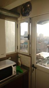 cocina con 2 ventanas y microondas en Confortable Apartment en Buenos Aires