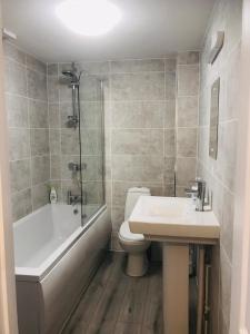 a bathroom with a tub and a toilet and a sink at Runnacleave Court in Ilfracombe