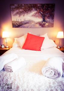 a bedroom with a bed with a red pillow and two lamps at The Rising Sun Inn in Waterlooville