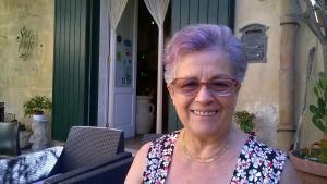 an older woman with glasses sitting on a porch at Sax Barisano in Matera