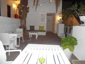 un patio blanco con una mesa y un árbol en Byzance Hotel, en Skala