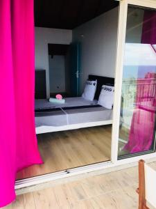 a room with a bed with a window and a pink curtain at 13 residence belle de nuit in Bouillante