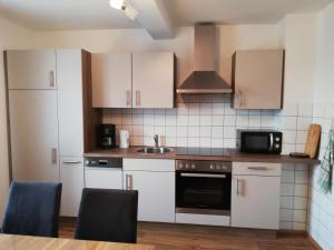 a kitchen with white cabinets and a sink and a microwave at Ferienwohnung Deisenberger in Furth