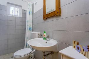 a bathroom with a sink and a toilet and a mirror at KUĆA ZA ODMOR- LOVRO in Mali Lošinj