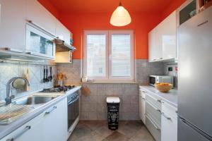 a kitchen with white cabinets and an orange wall at Horizont view apartment in Pula