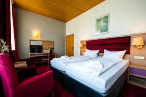 ein Hotelzimmer mit einem großen Bett und einem Stuhl in der Unterkunft Hotel Fränkischer Hof in Kitzingen