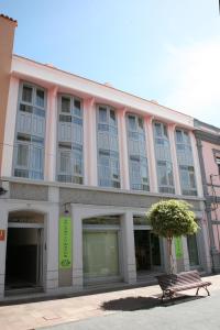 un edificio rosa con un banco delante en Apartamentos San Sebastián en San Sebastián de la Gomera