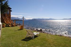 una silla blanca sentada en la hierba junto al agua en Hotel Huemul en San Carlos de Bariloche