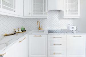 a white kitchen with white cabinets and a sink at Apartament Golden Place 2 in Kraków +46 photos