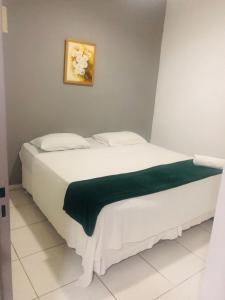 un letto bianco con una coperta verde sopra di HOTEL 44 a Goiânia