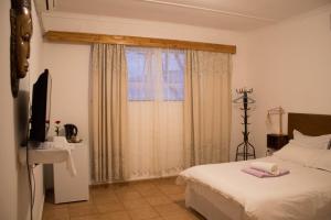 a bedroom with a white bed and a window at YoIeli Guest House in Windhoek