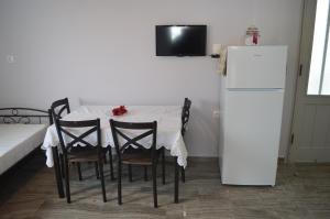 een eettafel met stoelen en een witte koelkast bij The Beach House in Nydri