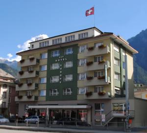 布里格的住宿－Hotel Europe Brig，一座大型绿色酒店建筑,前面设有停车场