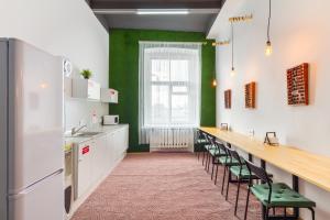 a kitchen with green walls and a long counter with chairs at Hostel 5Nebo in Moscow