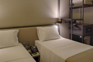 two beds in a room with a phone on a table at Slaviero Campina Grande in Campina Grande