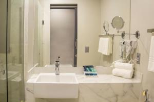 a white bathroom with a sink and a mirror at Slaviero Campina Grande in Campina Grande